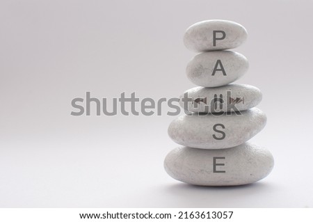 Yoga zen stones balancing on top of each other with pause symbol