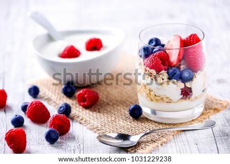 Yoghurt with forest fruits in glass.  Fresh morning healty breakfast. Raspberries, blueberries on white table.