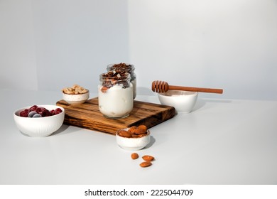 Yoghurts in glass jars with blueberries, raspberries and chia seeds and granola on a wooden board on a white background. The concept of healthy eating. Front view - Powered by Shutterstock