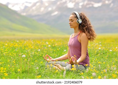 Yogi doing guided yoga tutorial with headphones in the mountain - Shutterstock ID 2192406079