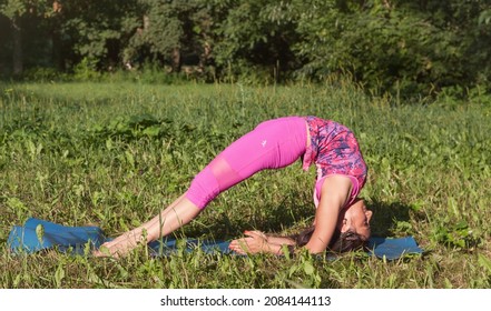 A yogi girl does a difficult asana standing on her elbows and her head thrown back. Ukraine, Dnipro.  4 August, 2018