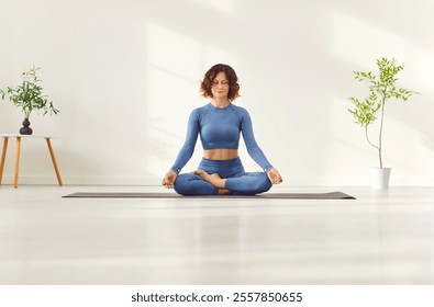 Yogi sporty attractive woman practicing yoga on white floor, doing Ardha Padmasana exercise, meditating calm in Half Lotus pose doing mudra gesture in home sport or modern studio fitness for health - Powered by Shutterstock