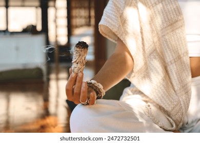 Yogi woman holding scented herbal stick in hand doing yoga breathing exercises. Burning aromatic incense smoky stick with meditating lady close up background. Aromatherapy smoke for healing practices. - Powered by Shutterstock