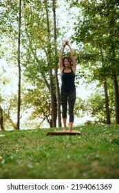 A Yogi Woman Practices Yoga In The Forest In Autumn. She Is In A Crescent Moon Yoga Pose.