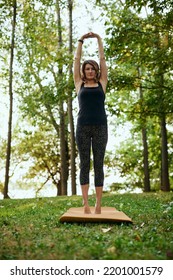 A Yogi Woman Practices Yoga In The Forest In Autumn. She Is In A Crescent Moon Yoga Pose.