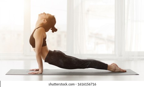 Yogi woman practicing yoga stretching pose, Cobra exercise, working out in light studio, side view - Shutterstock ID 1616156716