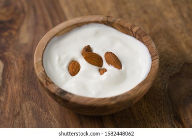 Yogurt With Almonds In Olive Wood Bowl On Wooden Table