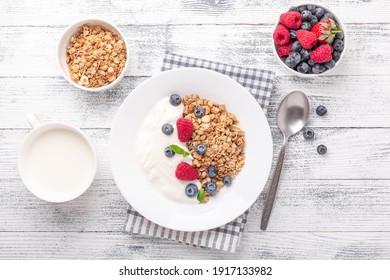 Yogurt with baked granola and berries in white ceramic plate on wooden background. Healthy breakfast. Copy space - Image - Powered by Shutterstock