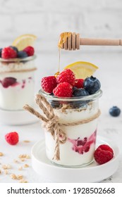 Yogurt With Berries, Cereals And Honey In A Glass On White Background, Vertical