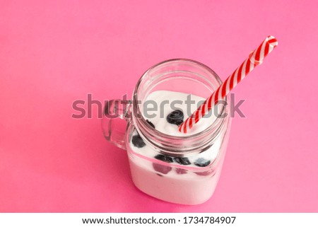 Yogurt with blueberries on a pink background in a glass jar