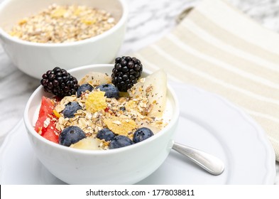 Yogurt bowl with blueberries, red berries and melon. In the background, bowl with cereals.