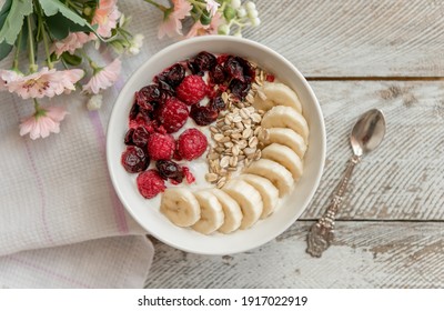Yogurt bowl with sliced bananas, raspberry and cranberry fruits. Oatmeal with fruits.