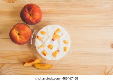 Yogurt with fresh peach slices on a wooden background