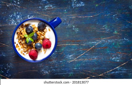 Yogurt with granola and fresh berries on an old wooden board with copy space for text. - Powered by Shutterstock