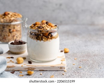 Yogurt and granola. Homemade baked muesli with rolled oats hazelnuts and chocolate pieces with fresh yogurt in glass jar. Healthy breakfast concept. Copy space. Morning table background. Close up food