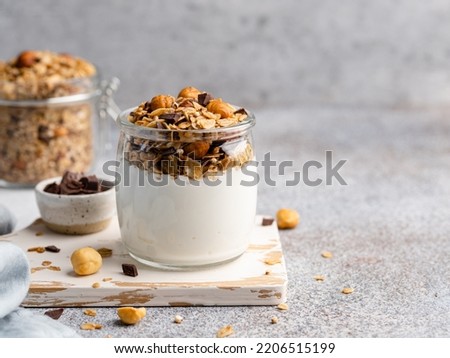 Yogurt and granola. Homemade baked muesli with rolled oats hazelnuts and chocolate pieces with fresh yogurt in glass jar. Healthy breakfast concept. Copy space. Morning table background. Close up food