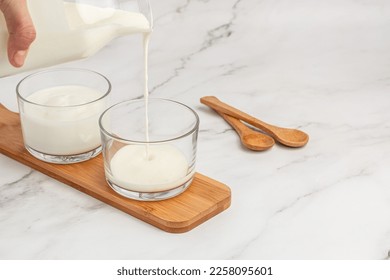 yogurt, kefir, fermented milk pouring into glass. Calcium rich diary product. banner, menu, recipe place for text, top view. - Shutterstock ID 2258095601