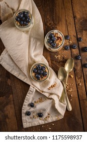 Yogurt Parfait With Blueberry And Granola. Healthy Breakfast Concept Served In Mason Jar With Decorative Spoons On Wooden Table.