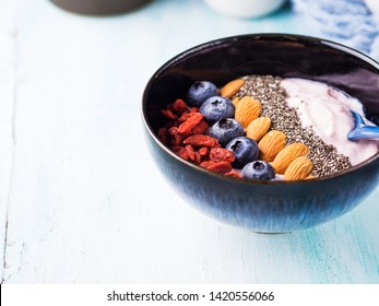 Yogurt Smoothie Bowl With Berries, Nuts, Chia Seeds On Pastel Turquoise Wooden Background. Plant Based Vegan Breakfast