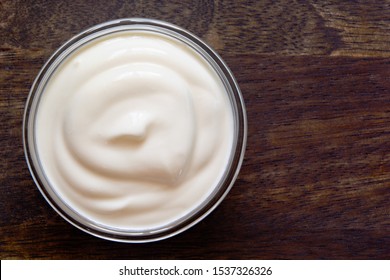 Yogurt, sour cream bowl on wood background. Healthy dairy food, white sauce portion close up