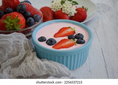 Yogurt, strawberries, blueberries on a light background