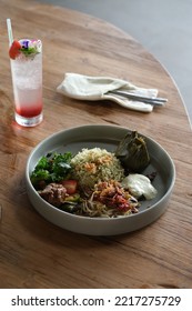 Yogya, Indonesia, August 9, 2022. Basil Rice With Kale, Plecing Bean Sprout And Botok On Deep Plate. A Glass Of Mocktail With Garnish As Flower. Fork And Spoon On The Back. Nasi Kemangi