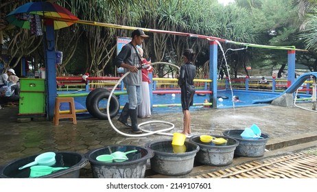 Yogyakarta, February 2022 : A Man Bathes A Child In A Small Pool On Parangtritis Beach.