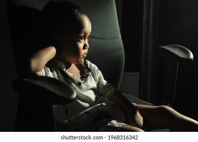 Yogyakarta, Indonesia - 04.05.2021: A Child Sits On A Chair With His Hand On His Head Who Is Watching YouTube