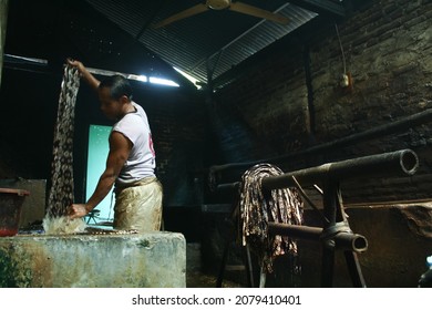 Yogyakarta, Indonesia: 06-16-2011: Old man washing batik cloth, one of the batik-making processes in Bantul, Yogyakarta