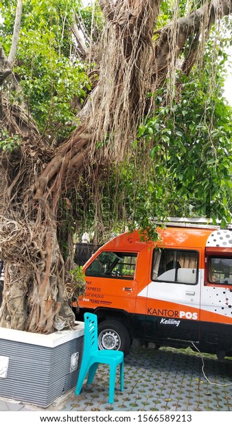 Yogyakarta, Indonesia / 21 November 2019 - mobile\
post car, position under Banyan tree in front of Yogyakarta\
immigration office, as a place to serve as a passport payment\
counter and others