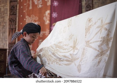 Yogyakarta, Indonesia December 25 2021 : Young Man drawing batik Indonesia is a traditional culture from Indonesia. Making Batik Tulis
