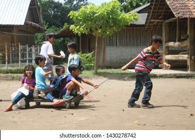 Yogyakarta, Indonesia - December 3, 2018: Children Playing In The Field, A Child Pulling Wooden Wagon That Many Children Ride