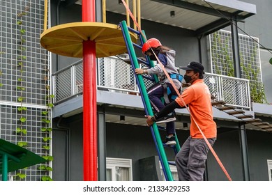 Yogyakarta, Indonesia - March 03, 2022: A Game Safety Officer Helps A Girl Climb A Ladder At Suraloka Zoo, Yogyakarta