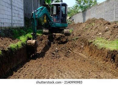 Yogyakarta, Indonesia. March 31, 2022. A worker is operating an excavator machine to dig the ground that will be used as a swimming pool. Making swimming pool. Excavator.  - Shutterstock ID 2140990983