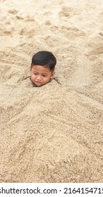 Yogyakarta,Indonesia - January 07 : a little boy buried in the sand of the beach Parangtritis Yogyakarta