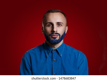 Yoing Male With Blue Glitter Beard On A Red Background Looking Into The Camera