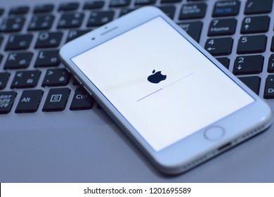 YOKOHAMA, JAPAN - October 12, 2018 : IPhone During IOS Update With Blurred Laptop PC Keyboard Background. IPhone Is Industry Leader Cellphone Brand & People Wait For New Features In IOS Update