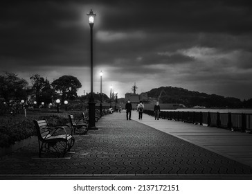 Yokosuka, Kanagawa Prefecture, Japan - October 7, 2021: Masked Japanese Out Walking On A March Evening At Verny Park With Japan Maritime Self Defense Force Ships In The Background.