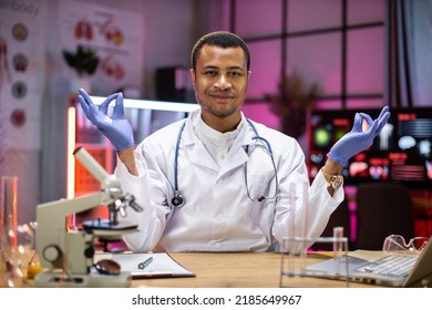 Yong African American Male Scientist Relaxing Practicing Yoga Wearing Lab Coat Working In Laboratory While Examining Biochemistry Sample In Test Tube And Scientific Instruments.