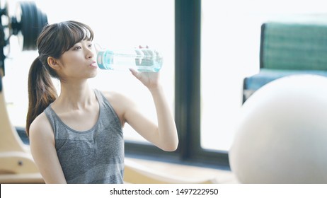 Yong asian girl in fitness gym. Rehydration. - Powered by Shutterstock