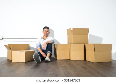 A Yong Asian Man Sitting On Floor Smiling With Boxes, Moving House