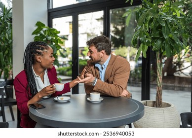 Yong happy business people, office workers, businessman and businesswoman sitting together in cafeteria, drinking coffee, taking a break from work, talking and discussing ideas and life themes. - Powered by Shutterstock