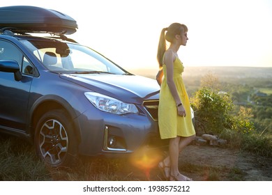 Yong glückliche Frau, die in der Nähe ihres Autos steht und bei Sonnenuntergang den Blick auf die Natur genießt. Reisekonzept und Reisekonzept.
