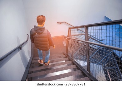 Yong man making steps down stairs in shopping center.