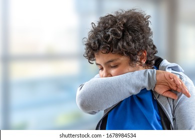 Junge Teenager niesen in seinen Ellenbogen, um zu vermeiden, andere infizieren.