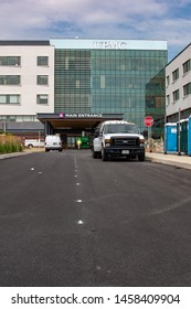 York, PA / USA - July 22 2019: Single Construction Worker Leaving Through Main Entrance Of New UPMC Hospital Construction Site