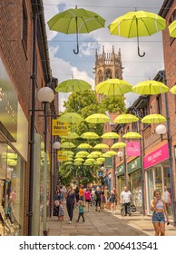 York, UK. July 2, 2021.  A Pedestrianised Street With An Overhead Display Of Yellow Umbrellas.  There Are Shops On Either Side And Shoppers Walk Up And Down.