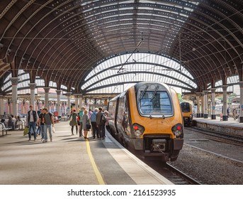 York, UK. May 19, 2022.  A train prepares to depart a railway station and passengers queue to board the train. An historic canopy is overhead.