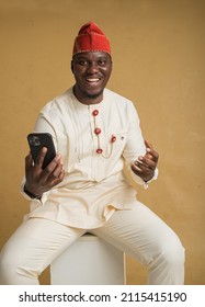 Yoruba Culturally Dressed Business Man Sitting with Phone in Hand Happy