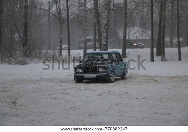 YOSHKAR-OLA, RUSSIA - DECEMBER 03,\
2017: Training in guided drifts on snow, ice and drifts into\
snowfall - drift on a rear drive car - on an empty car park in the\
city